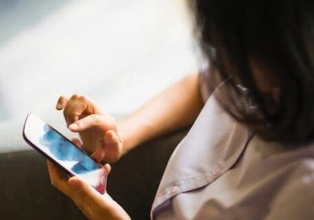 Young female sitting on sofa and swiping smartphone